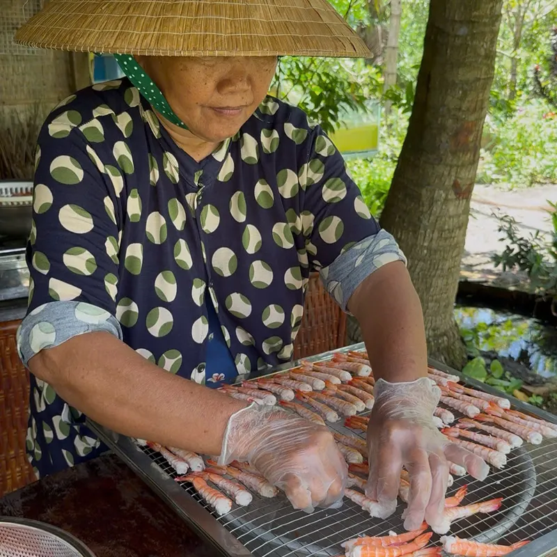 Cô Ba đeo găng xếp tôm lên vỉ sấy ngoài sân nhà